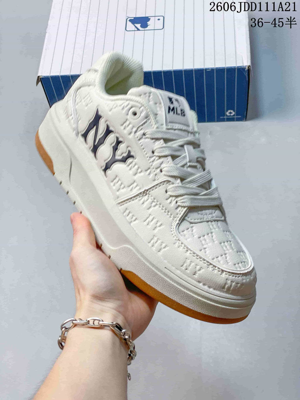 Angled side view of an ivory monogram sneaker with dark side branding