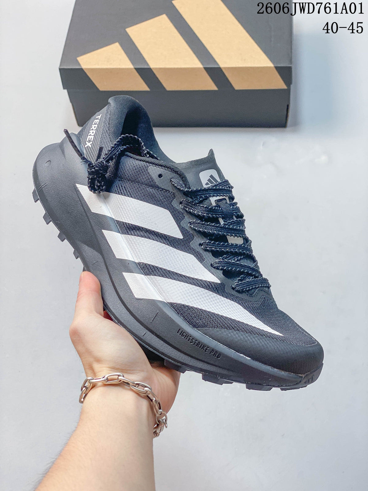 Dark gray Adidas Terrex trail running shoe with white stripes, a thick midsole, and lugged outsole