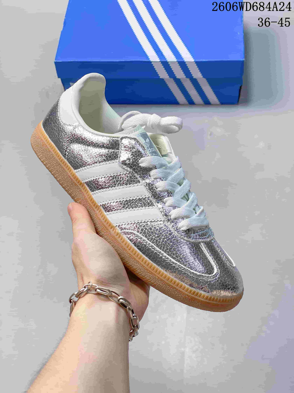Silver and white low-top sneaker with reflective-looking panels and gum-style sole.