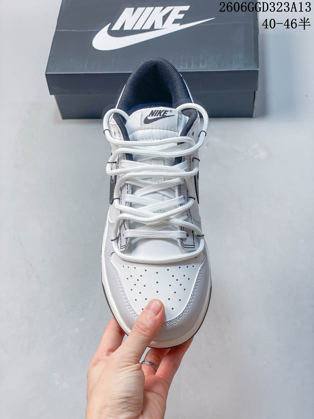 Front view highlighting the perforated toe and lace-up design of a white and navy sneaker