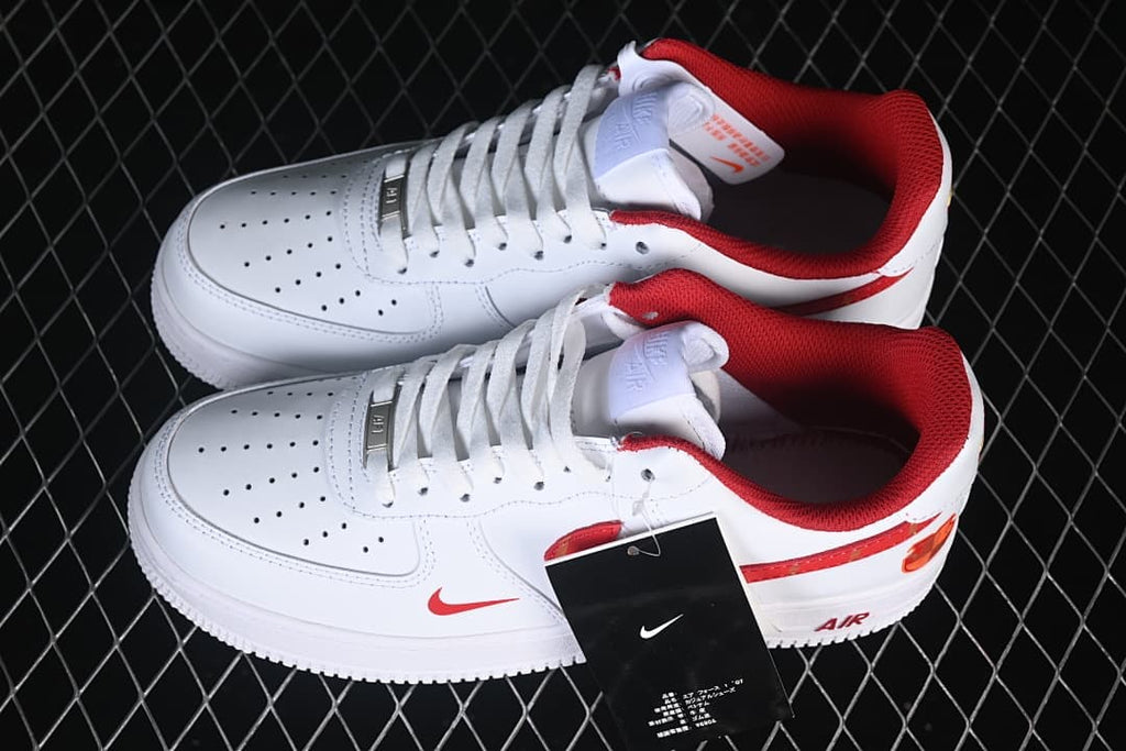Pair of white low-top sneakers viewed from above, with red collars and patterned side details.