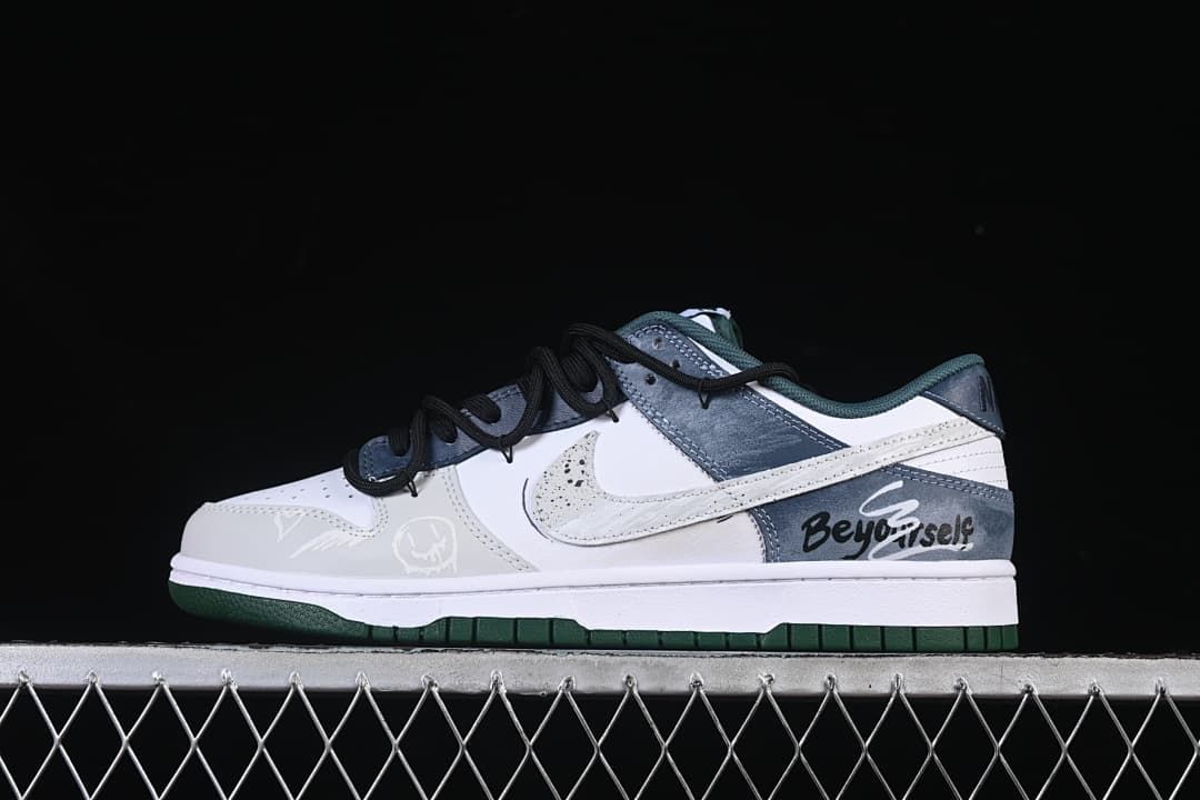 Side view of white, blue-gray, and dark green Nike SB Dunk Low sneakers with black laces and graphic side detailing