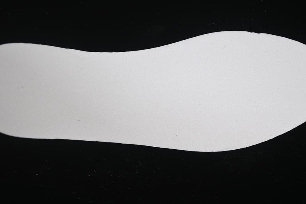 Plain light-colored shoe insole displayed on a dark background.