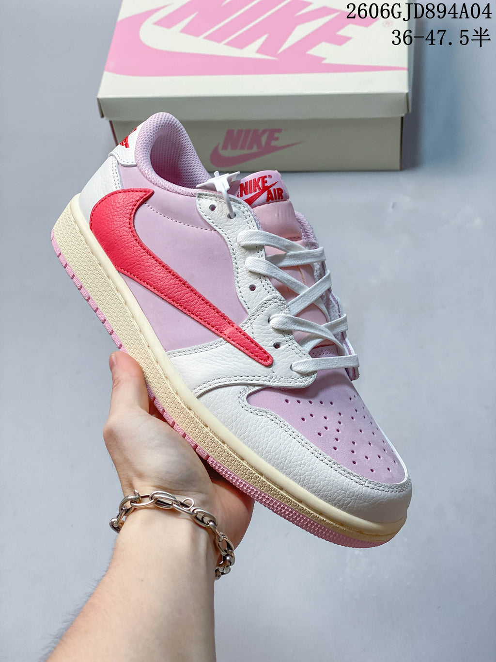 Close side view of a pink and white low-top sneaker with a red Swoosh