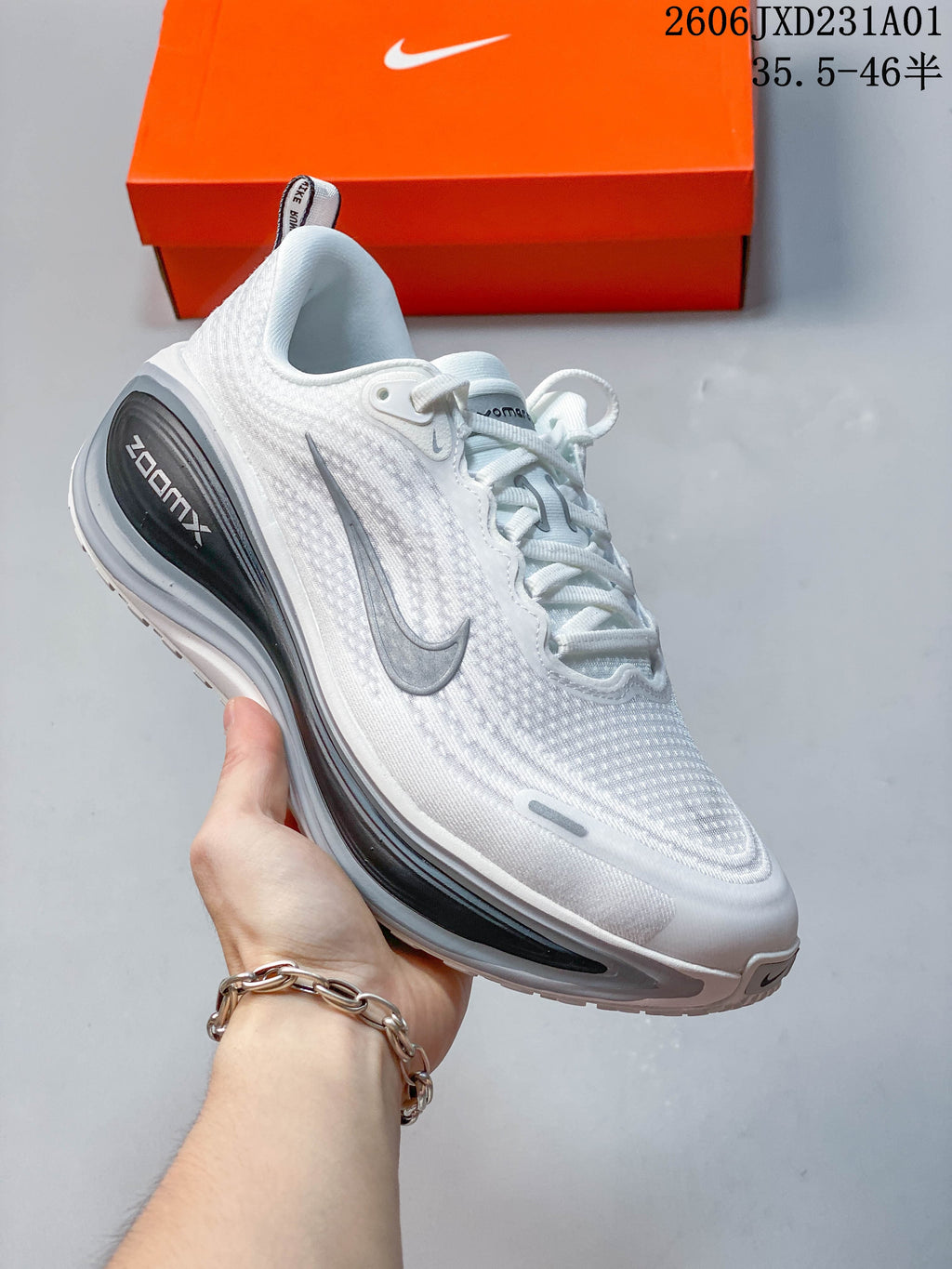 Side view of a white Nike Vomero Plus shoe with a gray Swoosh and dark heel detail.