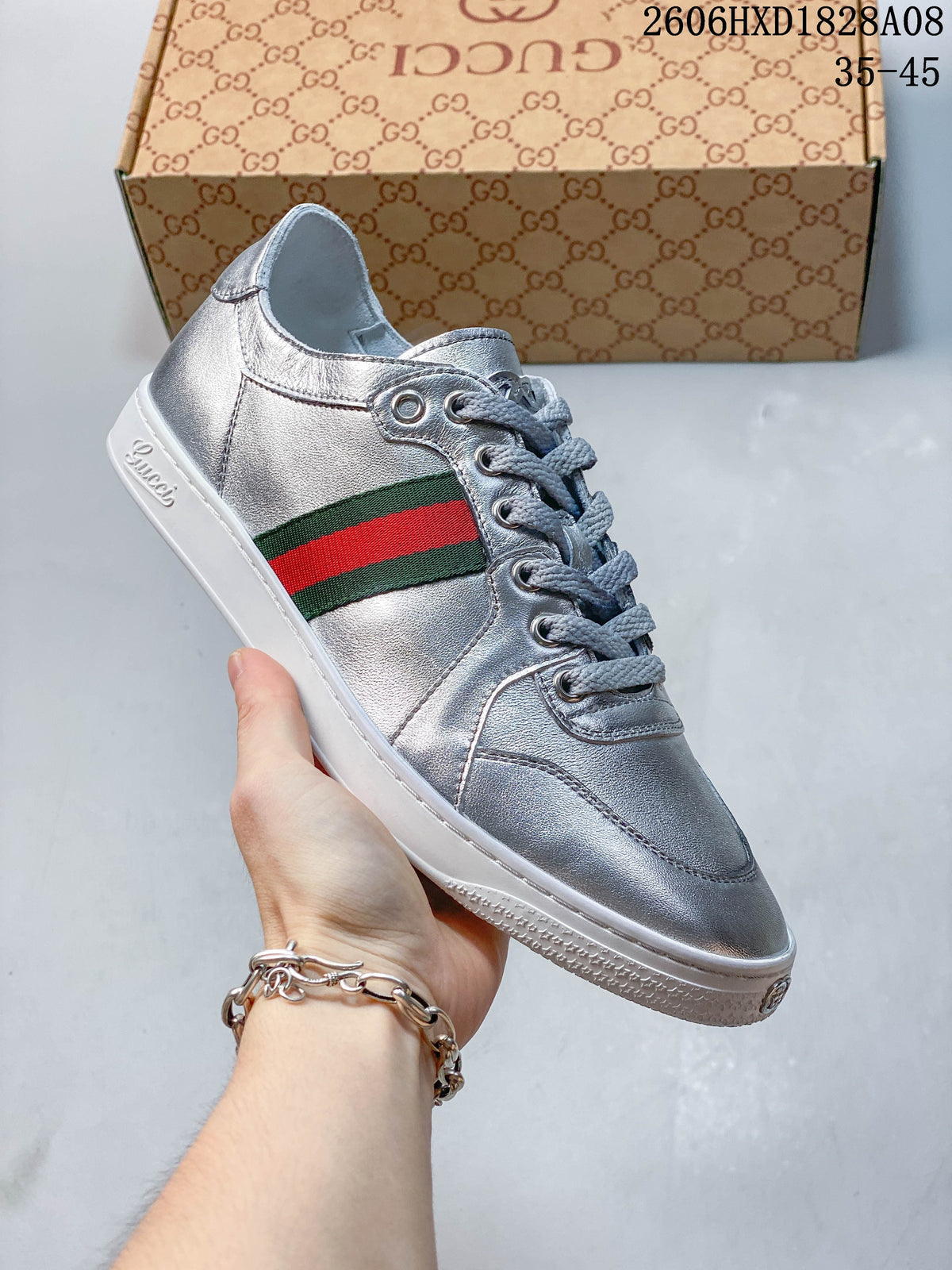 Angled side view of a silver low-top sneaker with a green-and-red stripe and white sole.