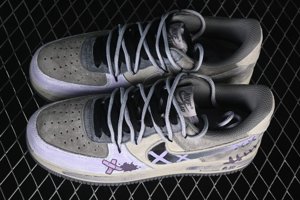 Pair of gray and cream Nike Air Force 1 low-top sneakers with lavender graffiti details