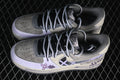 Pair of gray and cream Nike Air Force 1 low-top sneakers with lavender graffiti details