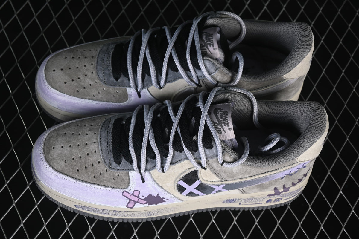Pair of gray and cream Nike Air Force 1 low-top sneakers with lavender graffiti details