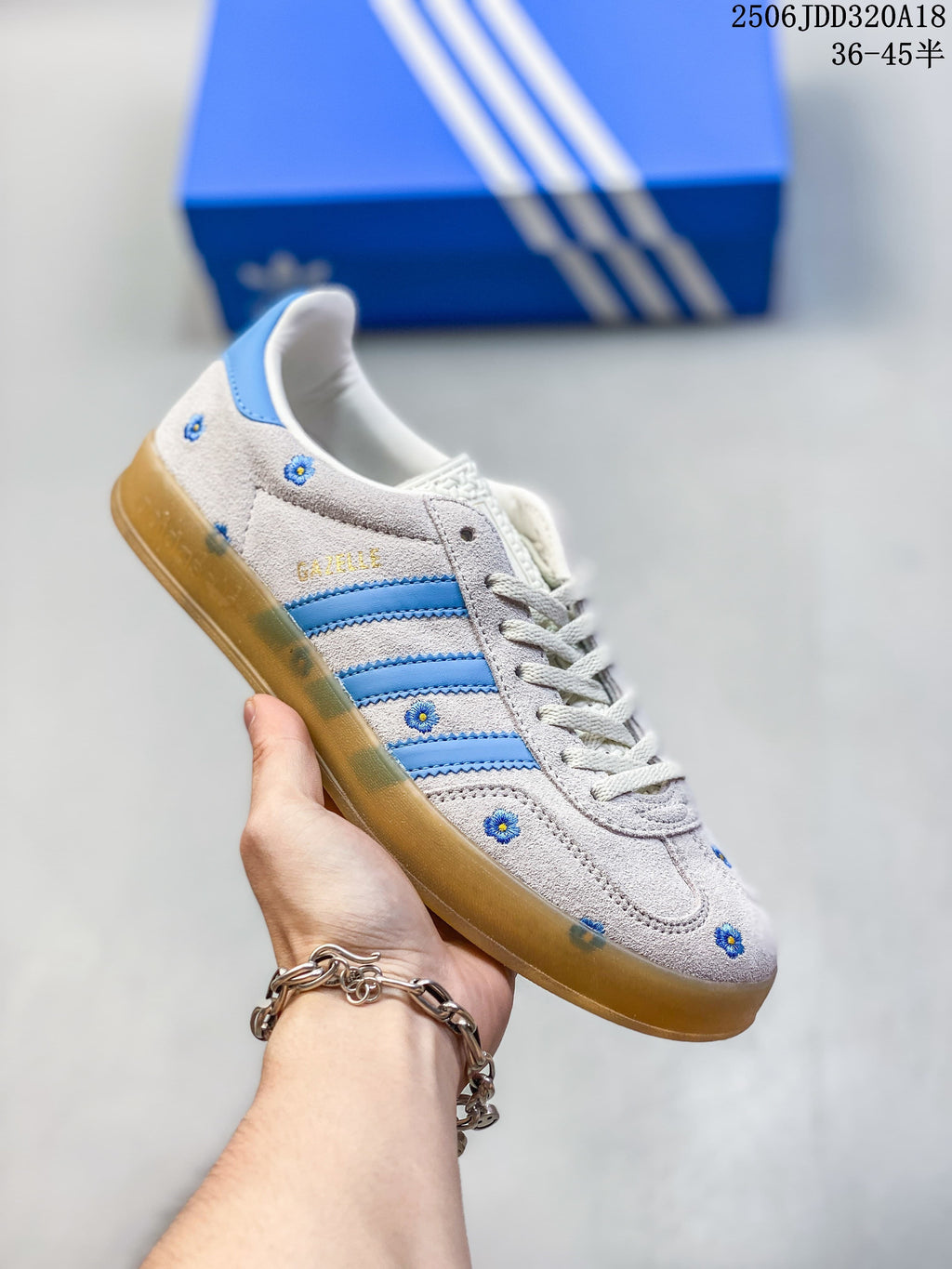 Light gray Adidas Gazelle 90 sneaker with blue stripes and small floral details