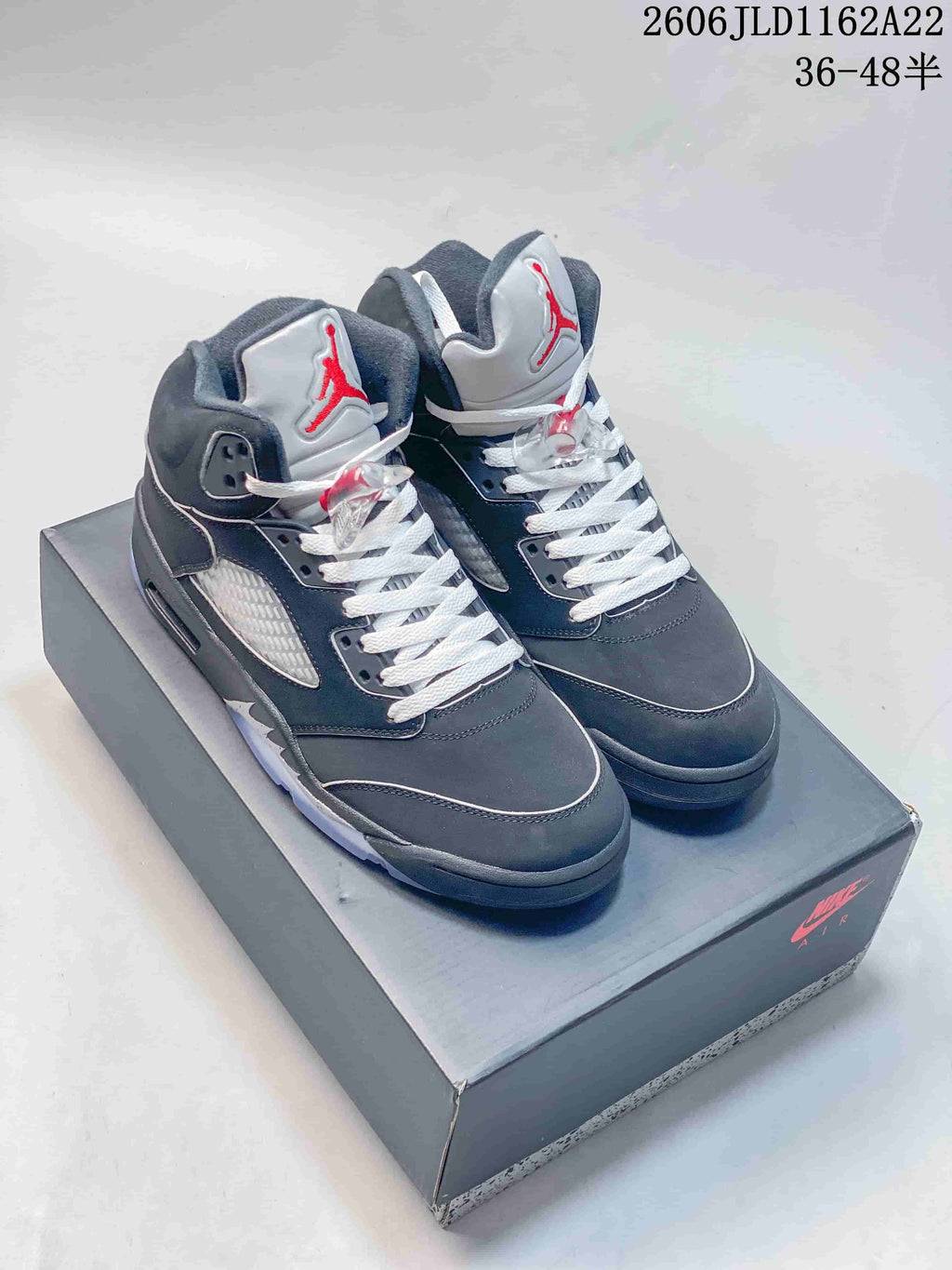 Pair of dark Jordan Air Jordan 5 high-top sneakers on a shoe box, shown from the front and side.