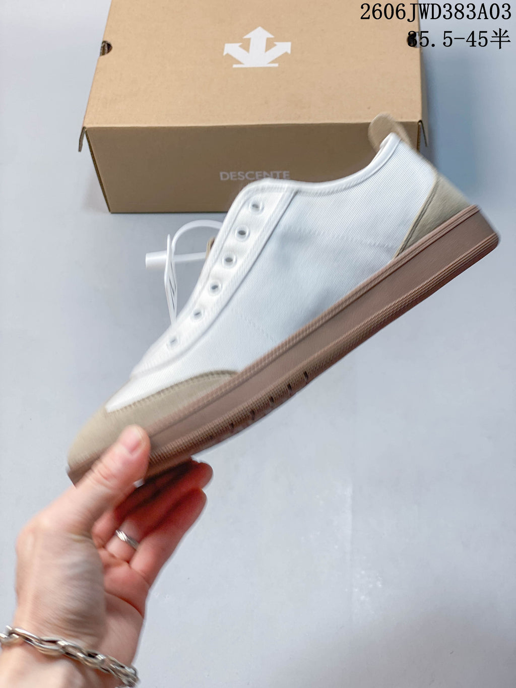 Side view of a white sneaker with beige toe and heel panels