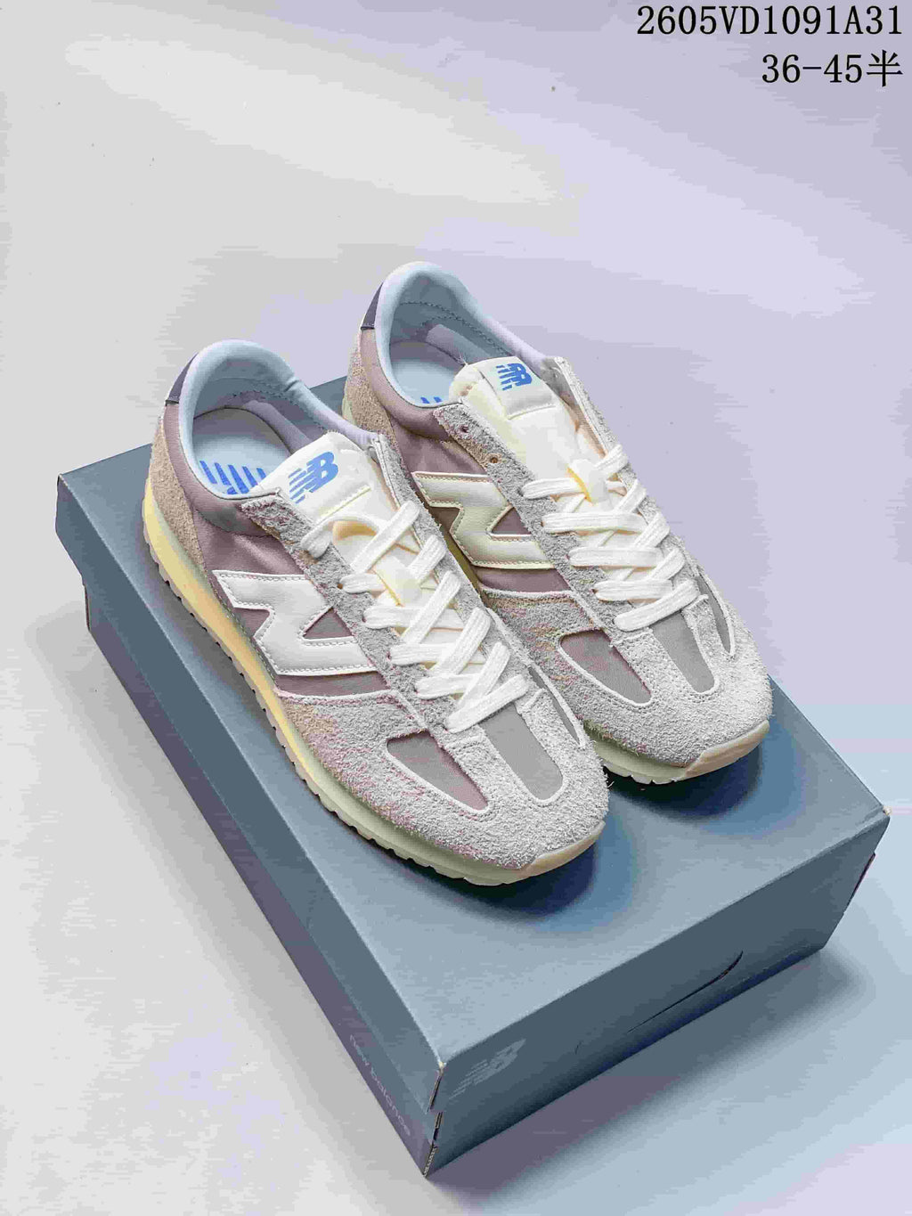 Pair of gray and cream New Balance 471 sneakers shown on a shoebox