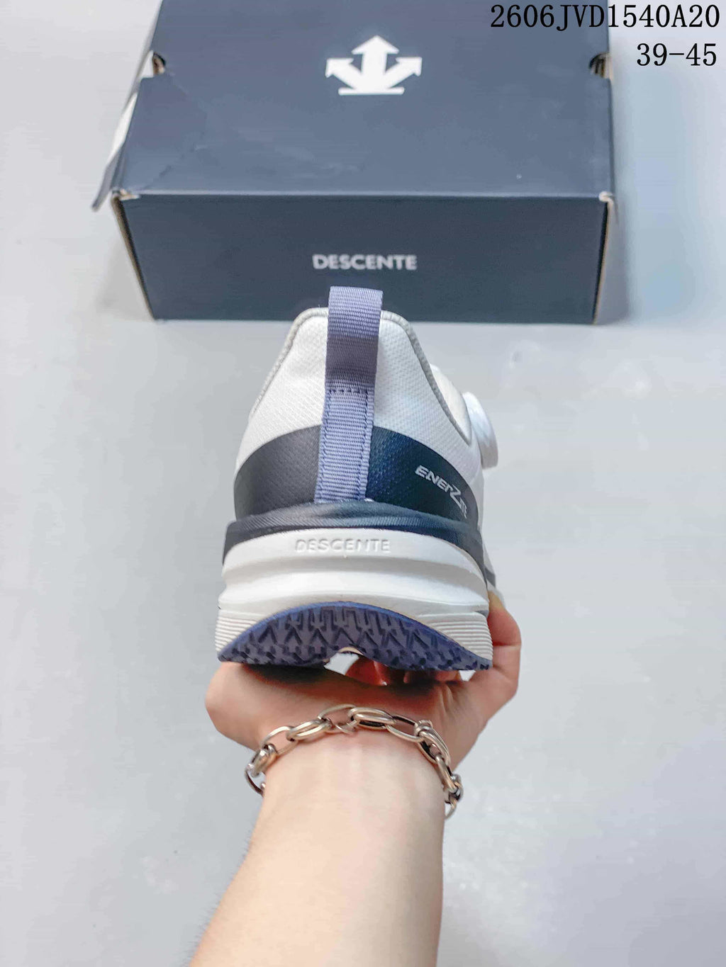Rear view of a white DESCENTE sneaker showing the heel pull tab and layered sole