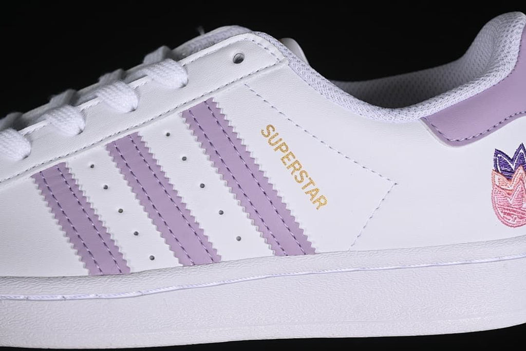 Close-up of the lavender three stripes and gold Superstar lettering