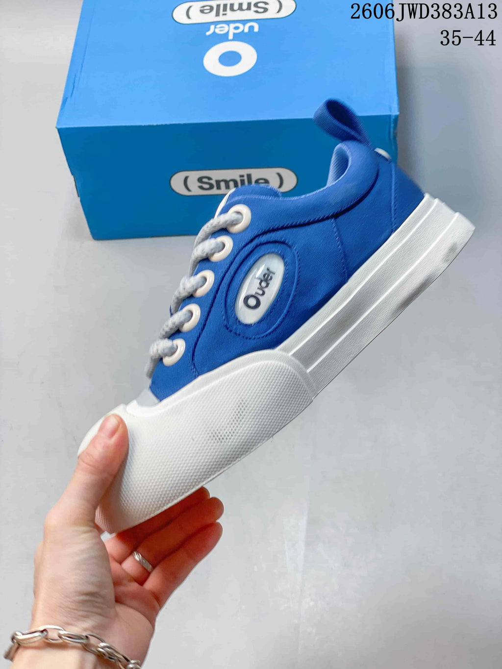 Side view of the blue low-top sneaker with a prominent white toe bumper and layered sole.
