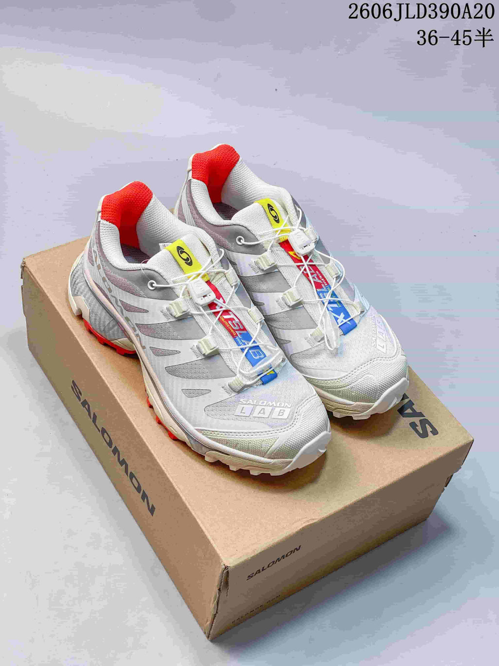 Pair of white and gray Salomon XT-4 OG shoes with red accents, shown on a branded shoe box.