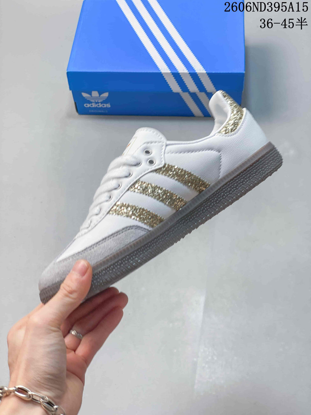 Side view of the white low-top sneaker with grey overlays and gold glitter stripes