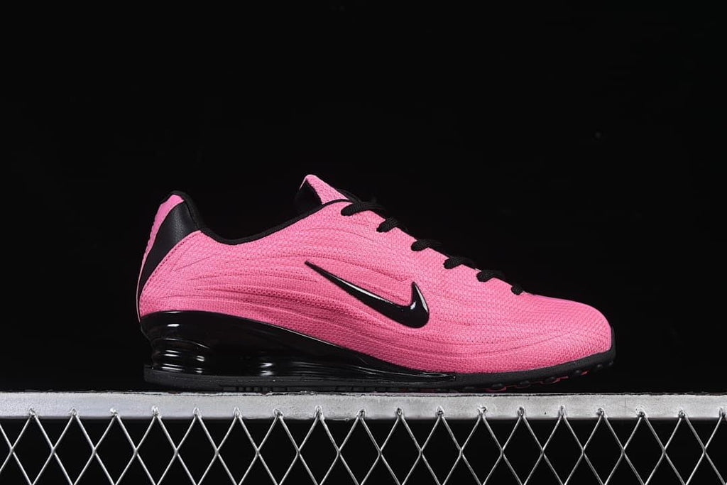 Side profile of the pink shoe with black Swoosh and Shox heel