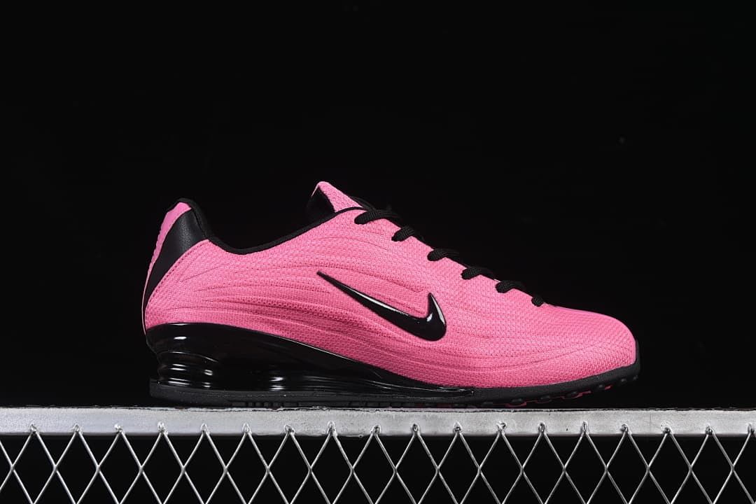 Side profile of the pink shoe with black Swoosh and Shox heel