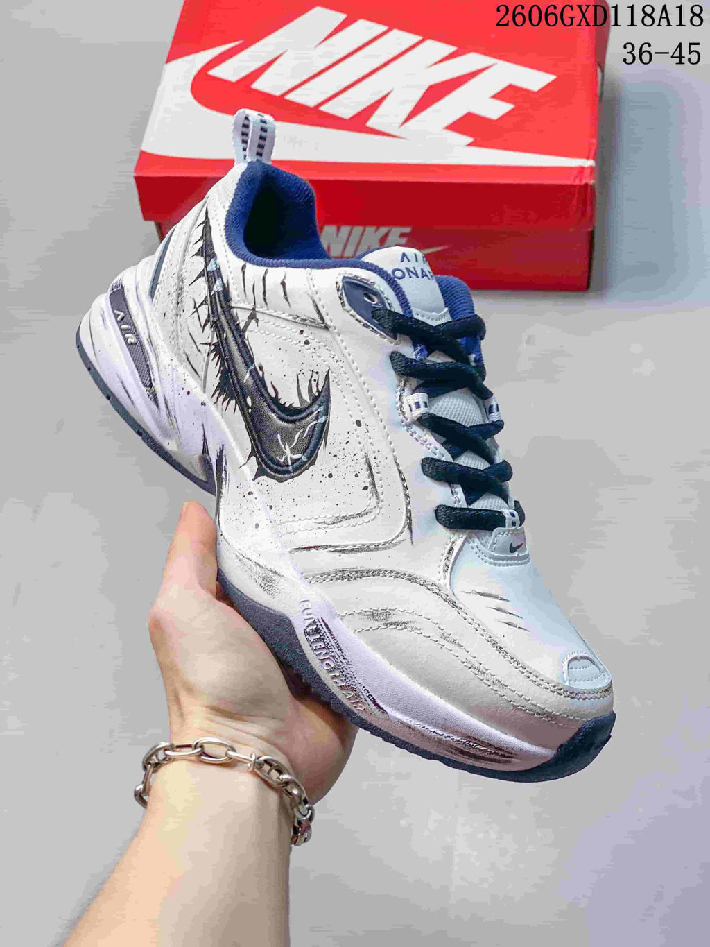 Angled view of a white Nike Air Monarch sneaker with navy accents, dark laces and graphic side details.