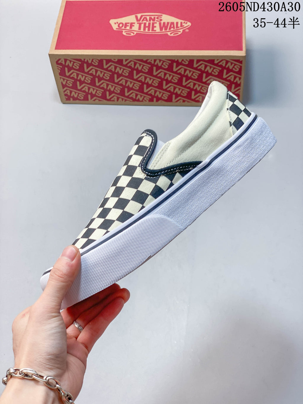 Side profile of a black-and-white checkerboard slip-on sneaker with a raised white sole.