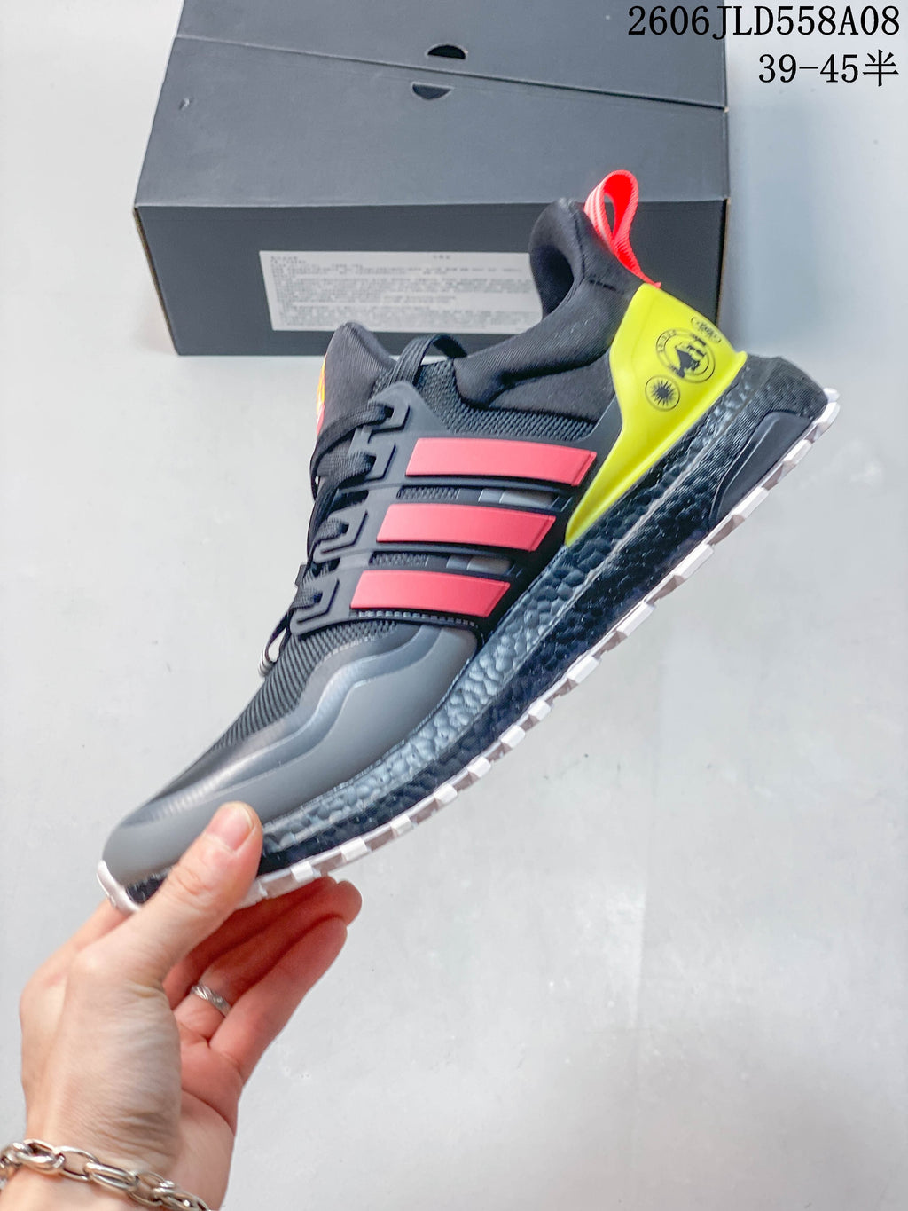 Side profile of a gray shoe with coral-red stripes, neon yellow heel detail, and textured midsole