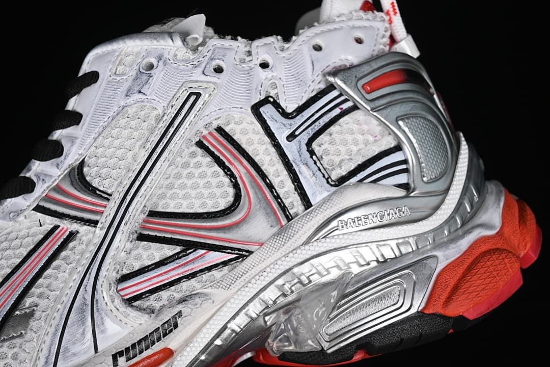 Close-up of the sneaker's layered side panels, silver-toned overlay and red outsole accents.