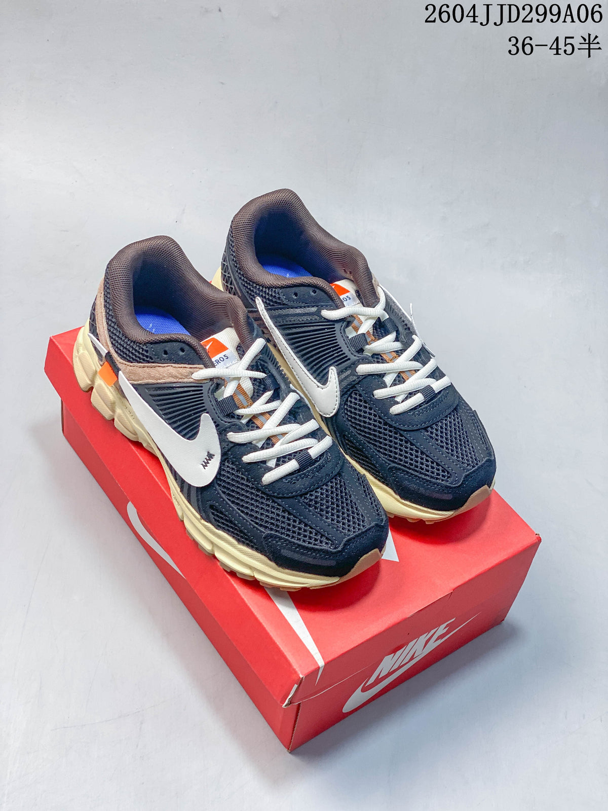 Pair of navy Nike Zoom Vomero 5 sneakers with pale midsoles on a red box