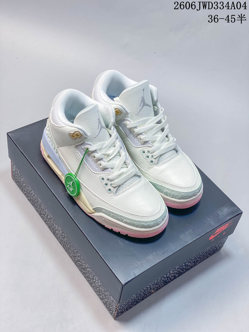 Pair of white Air Jordan 3 Retro sneakers with pale mint and pink accents on a shoebox