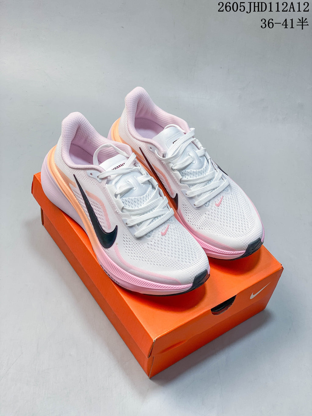 Pair of white and pink Nike Air Zoom Pegasus 42 running shoes displayed on an orange box.