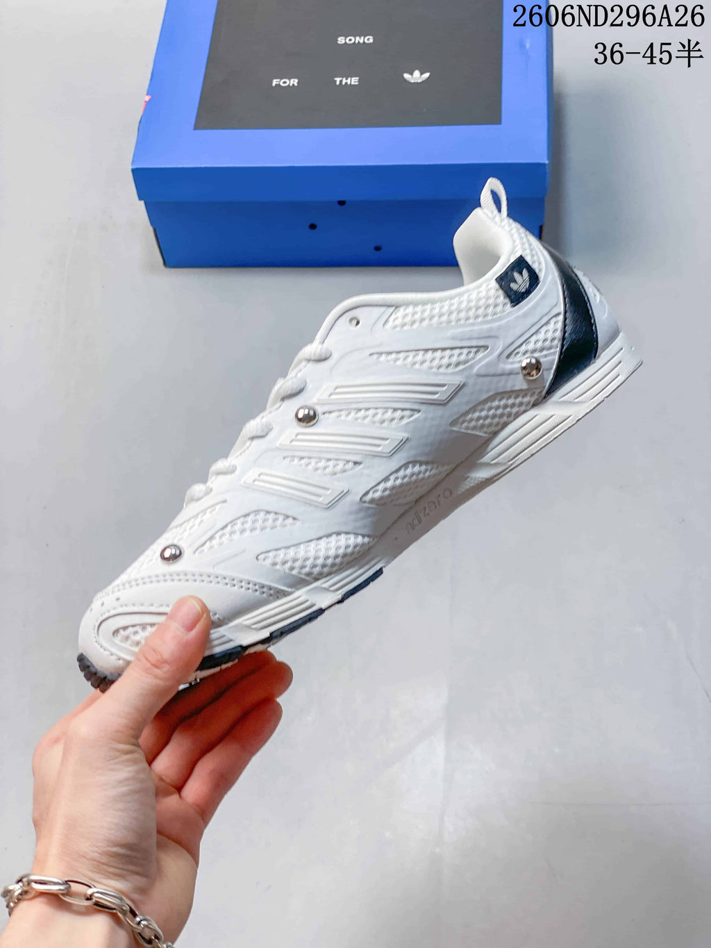 Side view showing the white sneaker’s layered panels and metallic-tone details