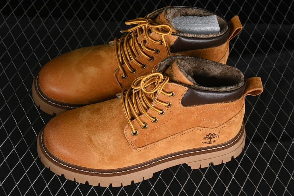 Pair of yellow-brown mid-top boots with plush lining and lugged soles.