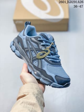 Blue-gray ASICS GEL-NYC RGD sneaker shown from the side with a decorative oval lace accessory; image text shows code 2601JGD291A26 and sizes 36–47.