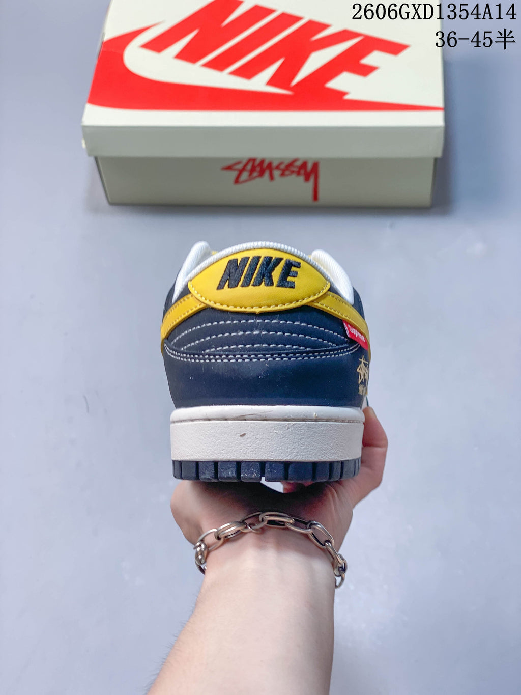 Rear view of the sneaker showing a yellow heel panel, navy overlays and white stitching.