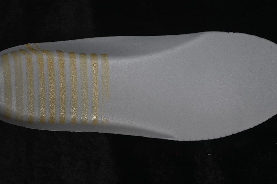 Close-up of a light-colored insole with gold-tone printed marks