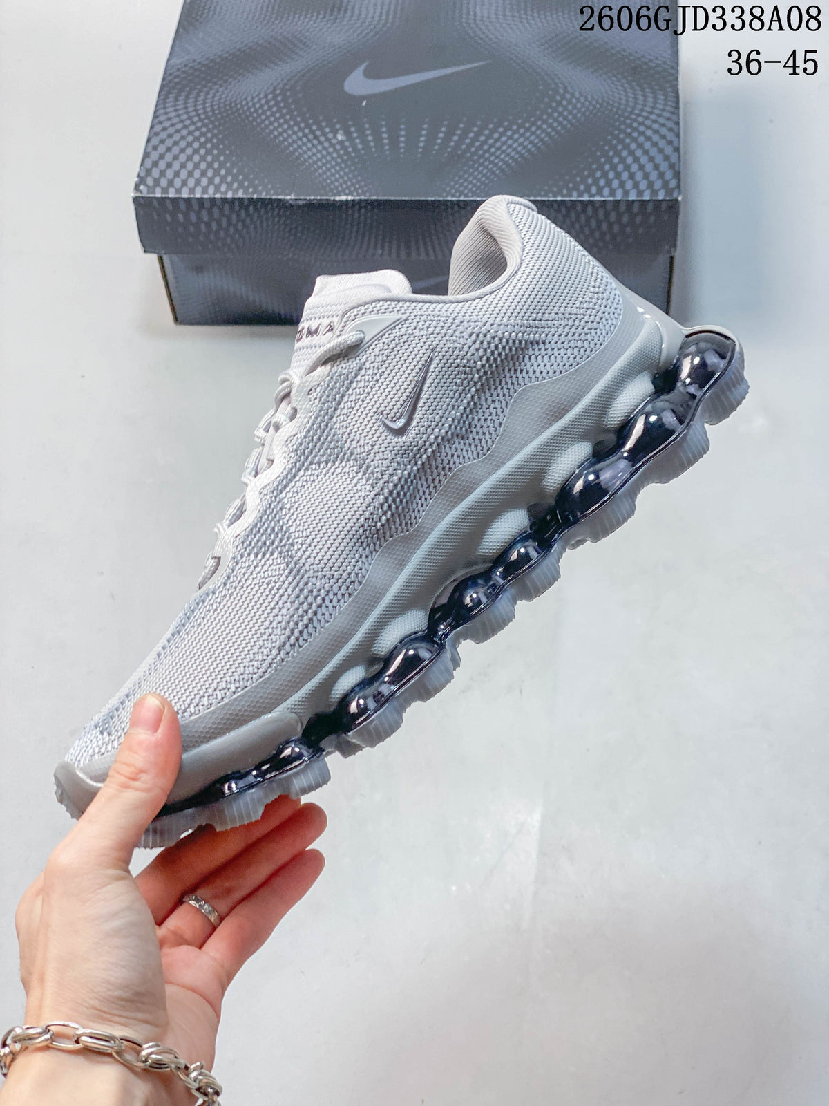 Side profile of a light grey Nike Air Liquid Max sneaker showing its segmented sole