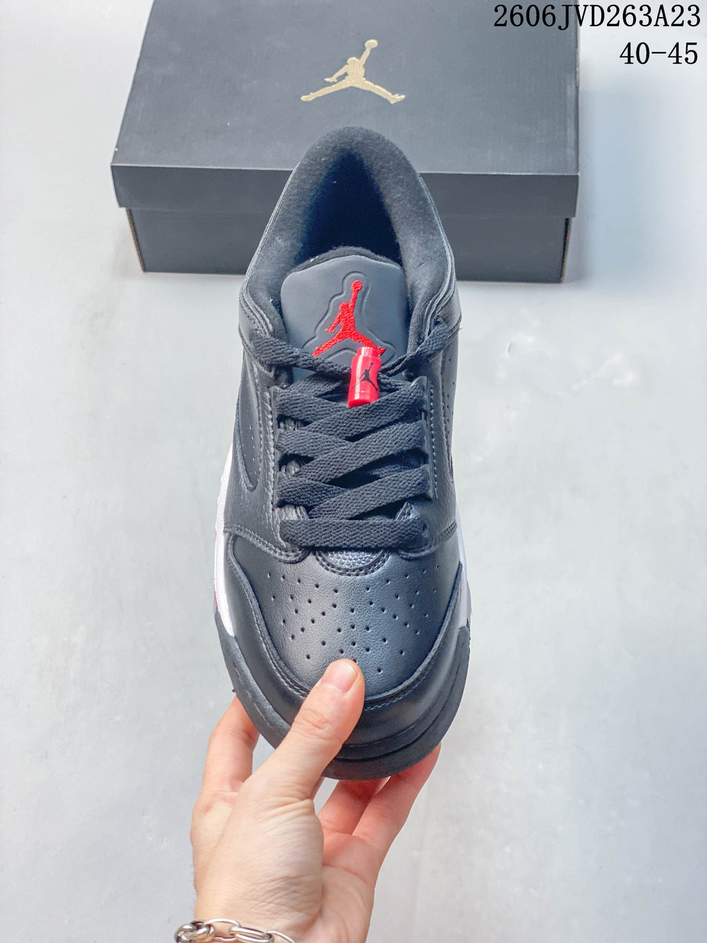 Front view of the shoe with dark laces and a red tongue logo.