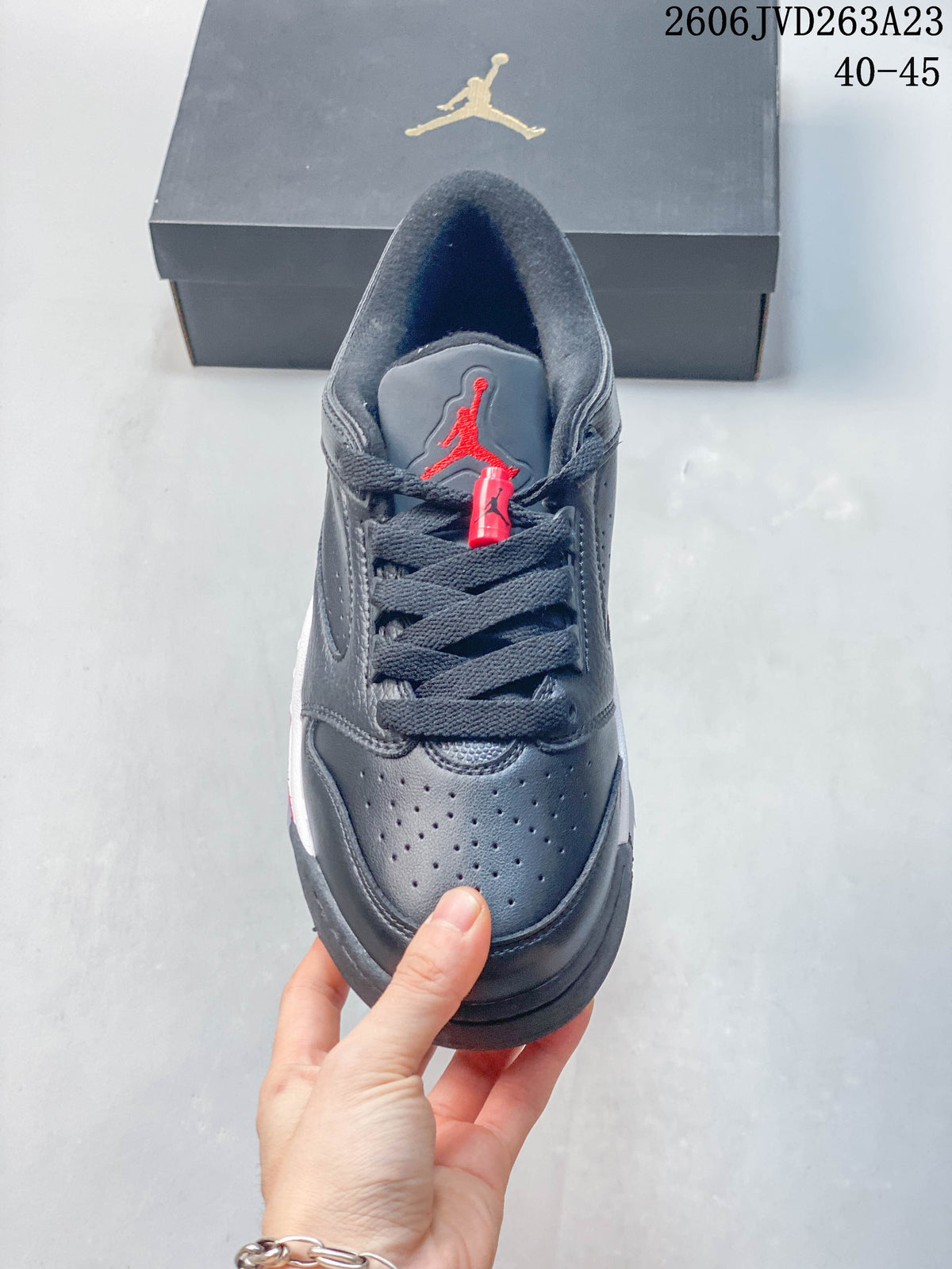 Front view of the shoe with dark laces and a red tongue logo.