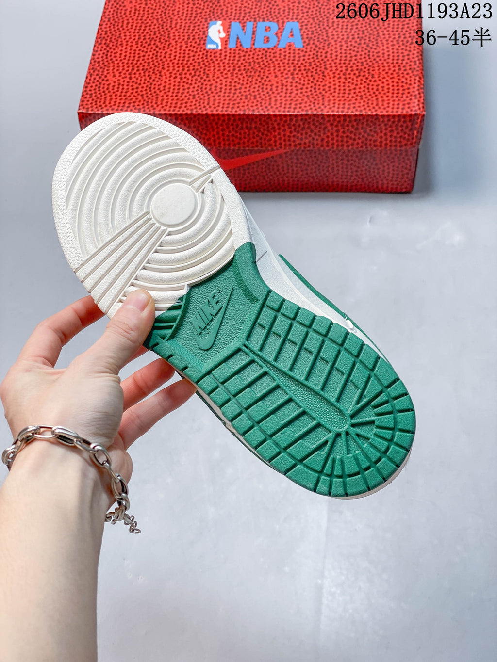 Underside of a sneaker showing a green-and-white outsole, with an NBA-branded box behind it