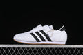 Side view of a white adidas Taekwondo shoe with black stripes and a gum-colored outsole.