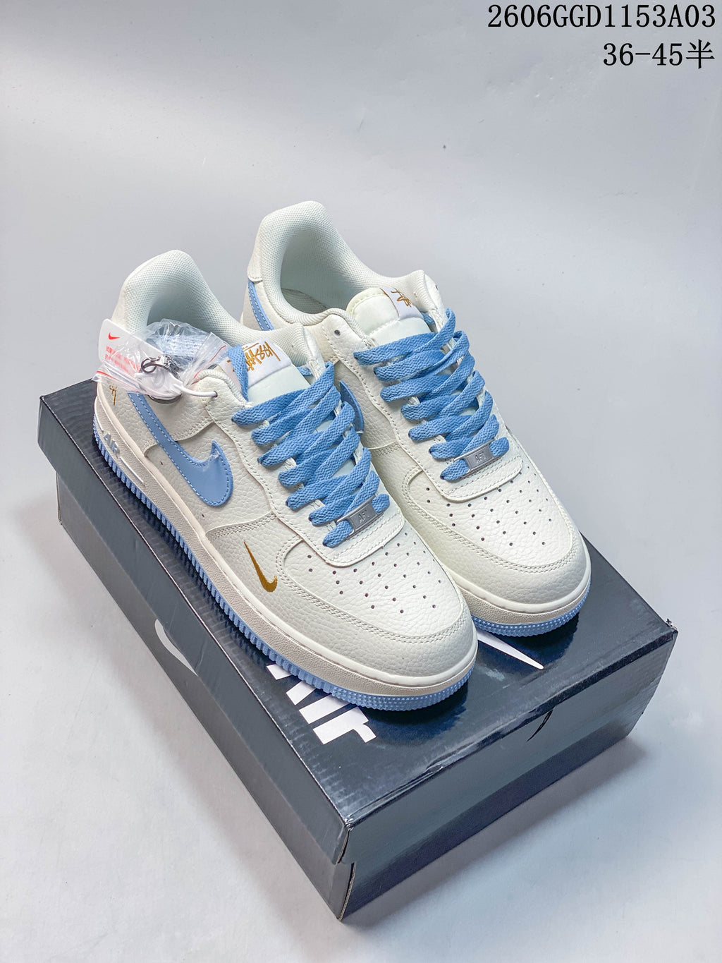Pair of off-white and light blue low-top sneakers with gold-tone accents, shown on a shoebox