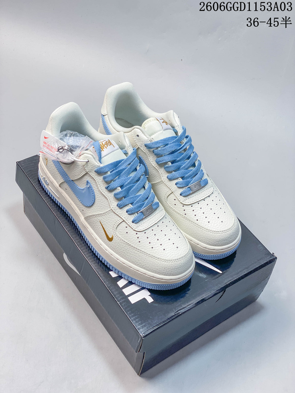 Pair of off-white and light blue low-top sneakers with gold-tone accents, shown on a shoebox