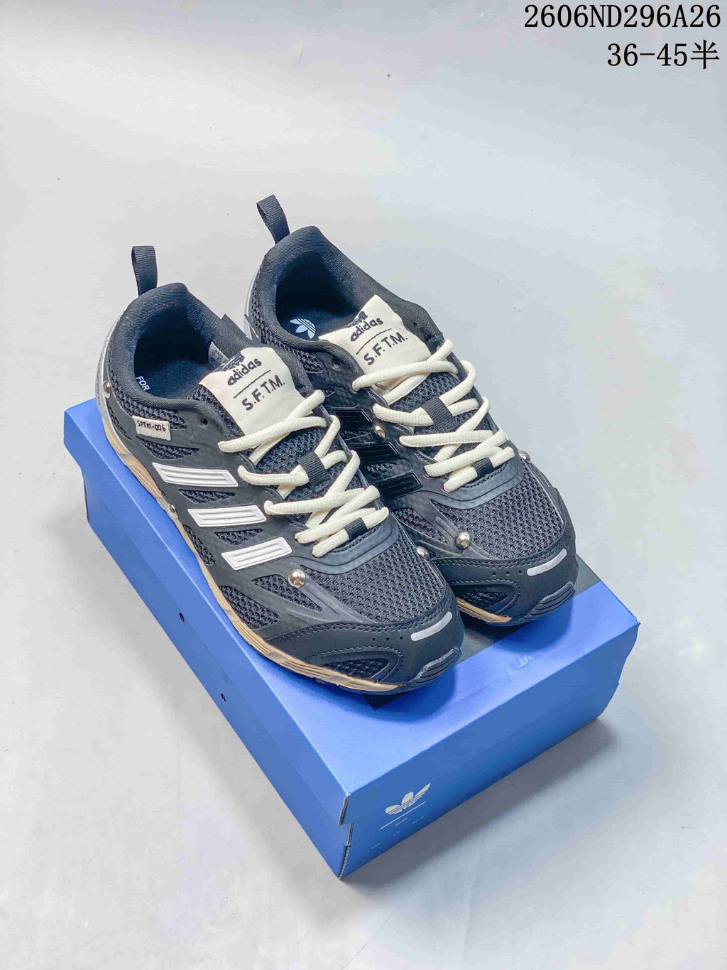 Pair of dark gray Adidas Originals PR SFTM low-top sneakers with light laces on a blue box