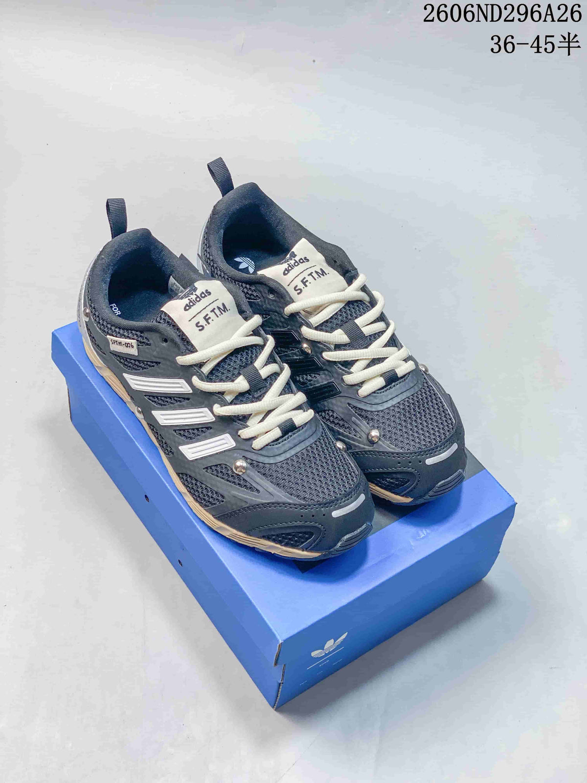 Pair of dark gray Adidas Originals PR SFTM low-top sneakers with light laces on a blue box