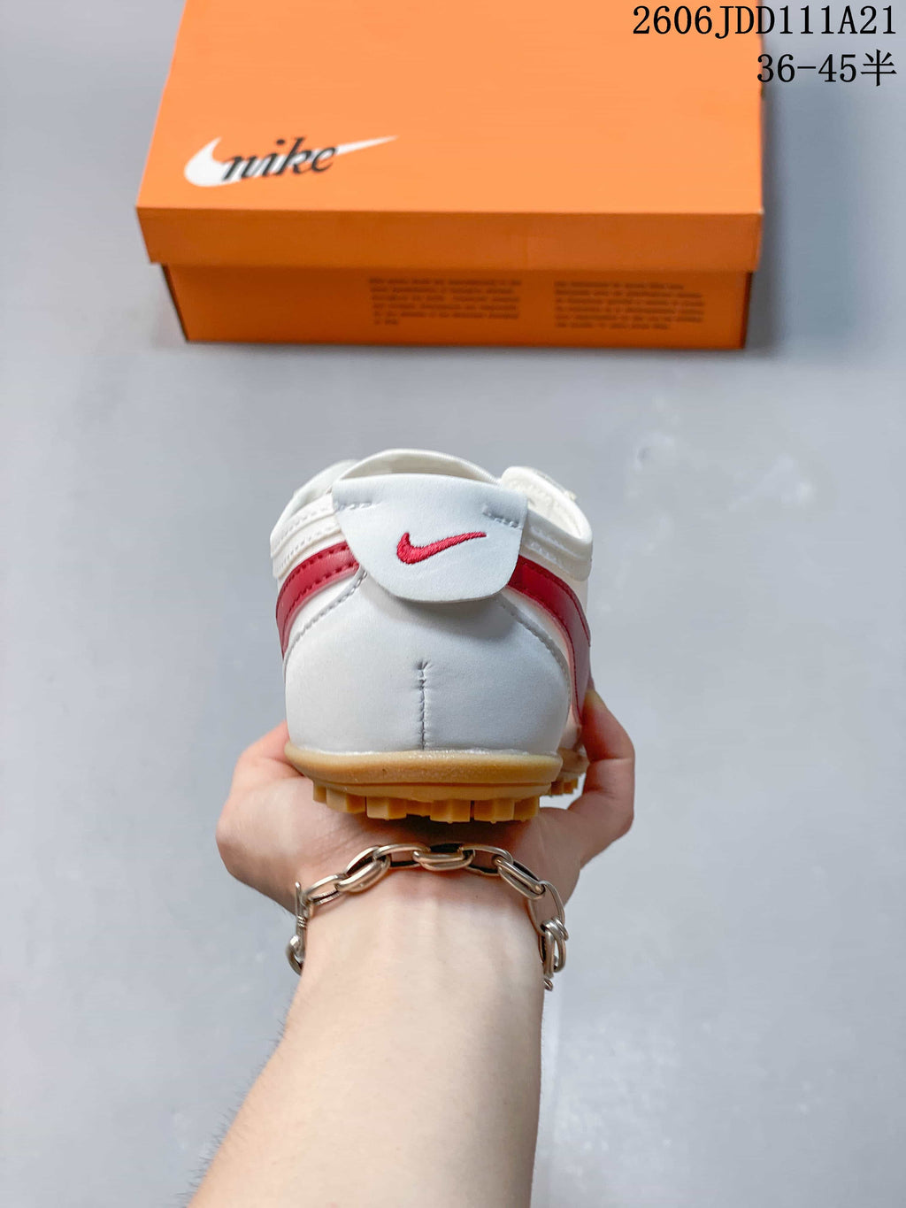 Heel view of a white sneaker with red rear detailing and gum-colored outsole