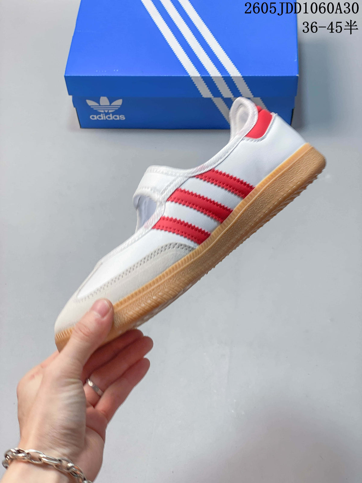 Side profile of the white Samba Jane sneaker with red stripes, strap closure, and gum-colored sole