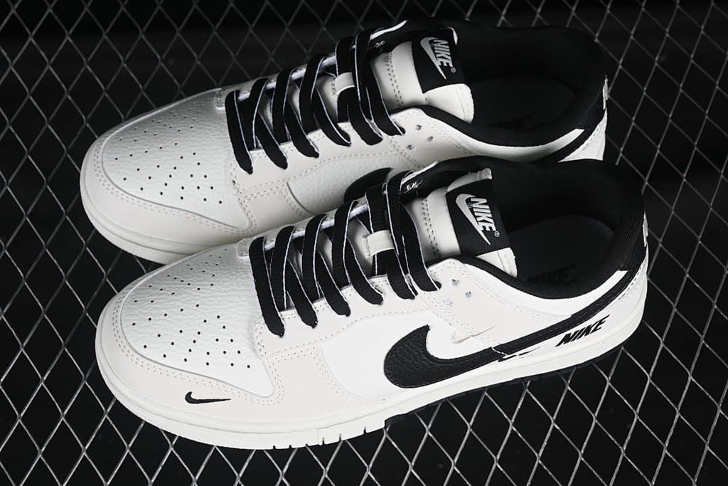 Top view of a pair of white and black low-top sneakers with black laces and perforated toe panels.