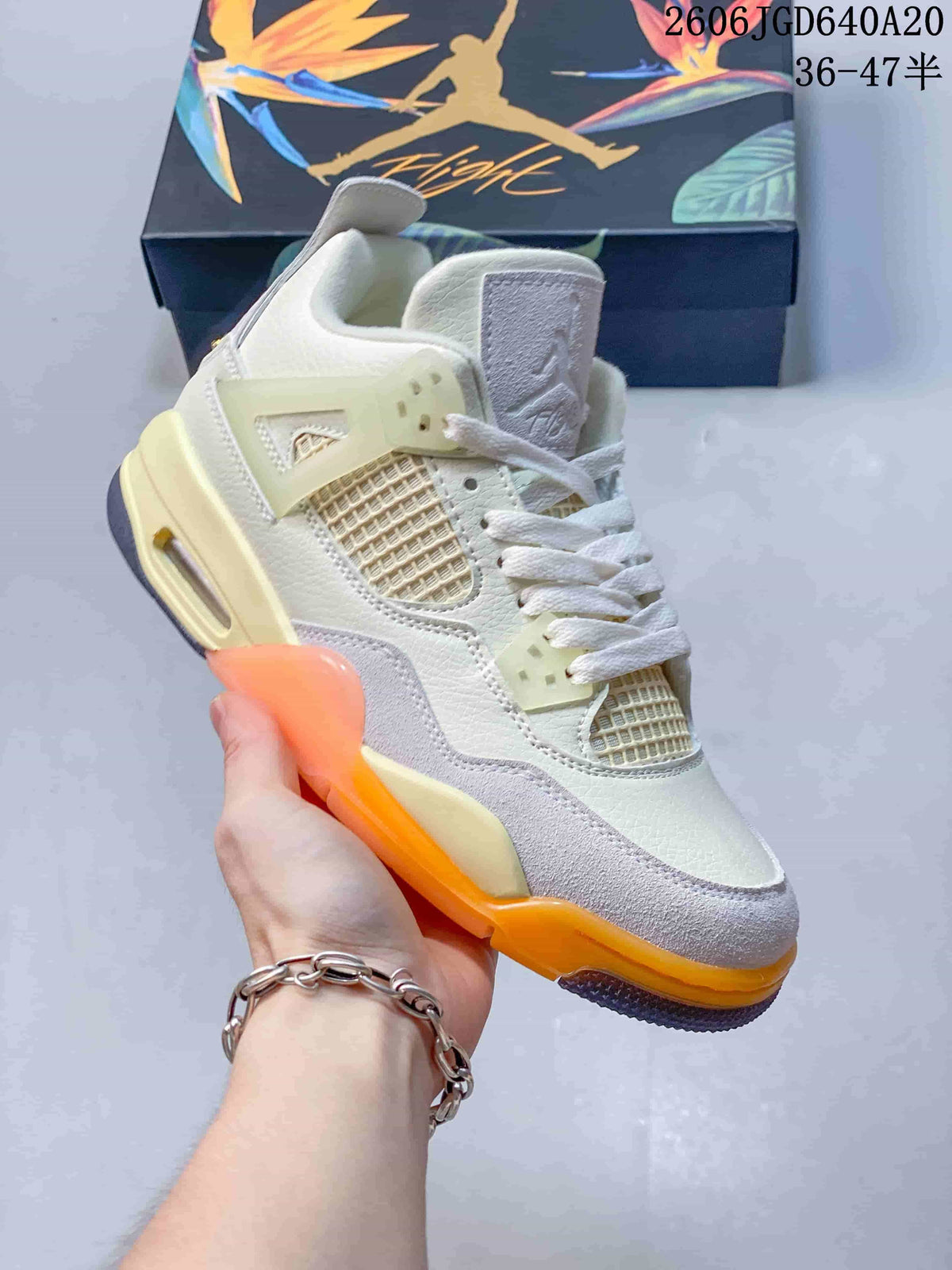 Angled close-up of the beige and gray sneaker with orange outsole details