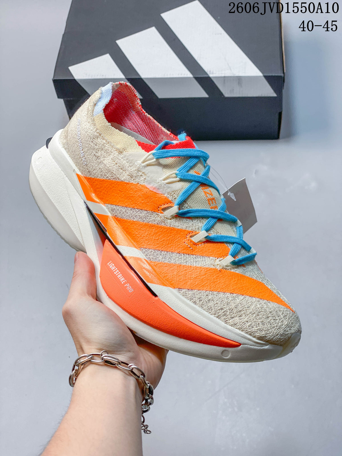 Close side view of the cream Adidas running shoe with orange stripes and a sculpted sole.